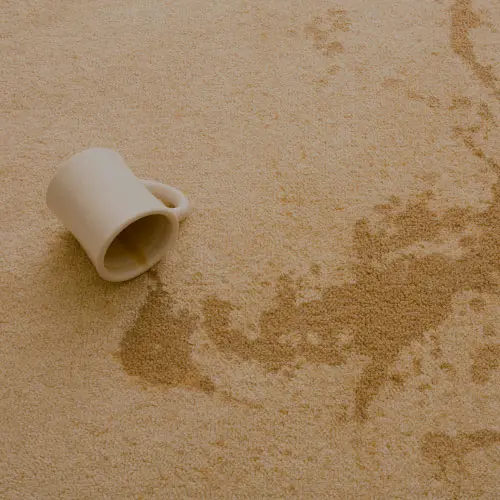 A tipped mug and coffee stain on a light carpet